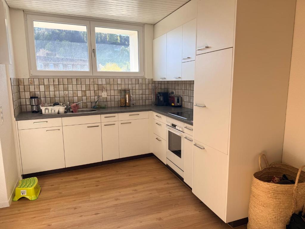 eine Küche mit weißen Schränken und einem Fenster in der Unterkunft Oumaya in Erlach