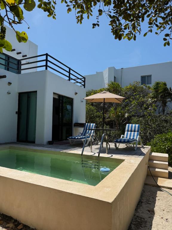 a swimming pool with two chairs and an umbrella at Casa Nora in Sisal