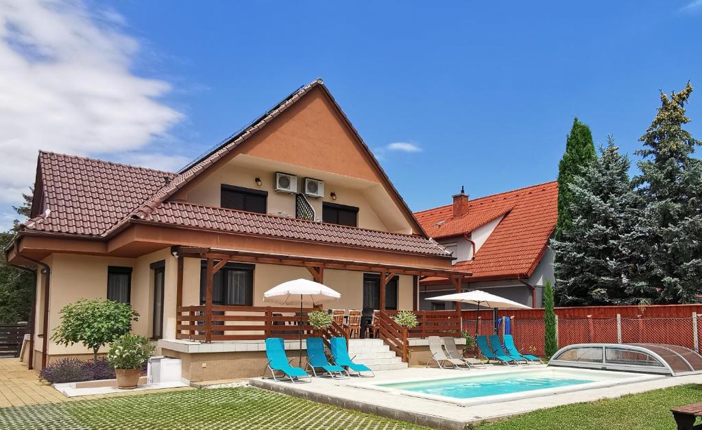 a house with a swimming pool and blue chairs at Kovács Apartmanház in Balatonfüred