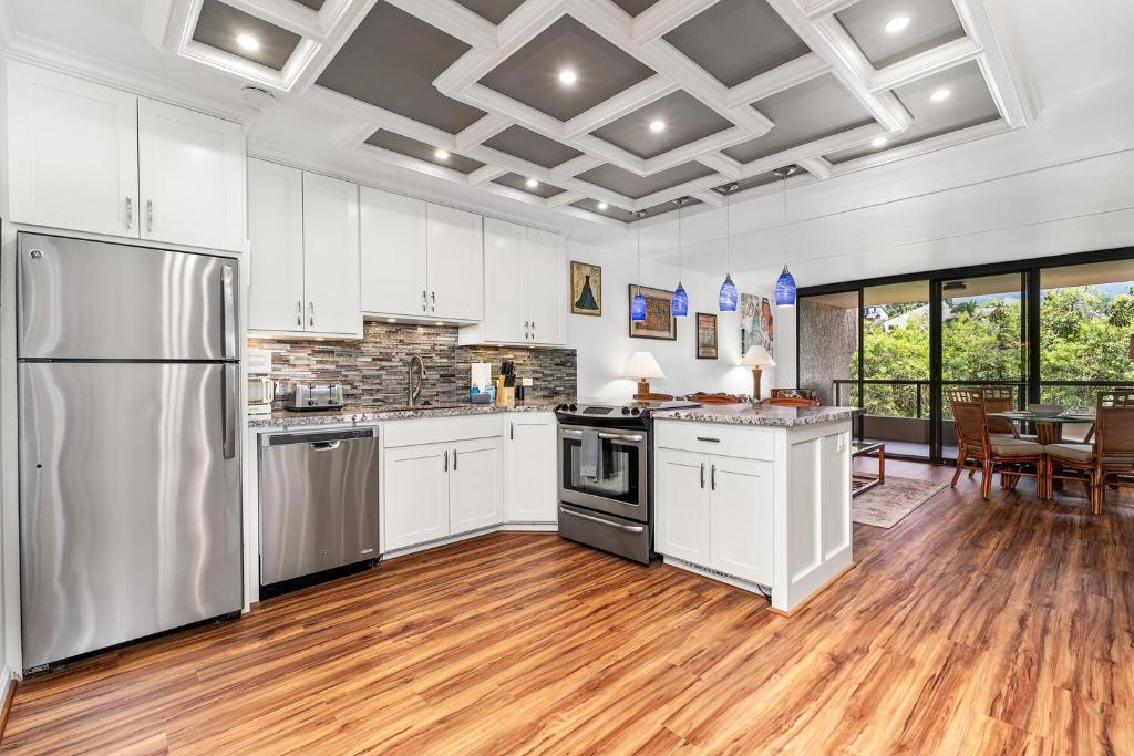a kitchen with white cabinets and stainless steel appliances at Kona Pacific E629: Beautifully Remodeled condo! in Kailua-Kona