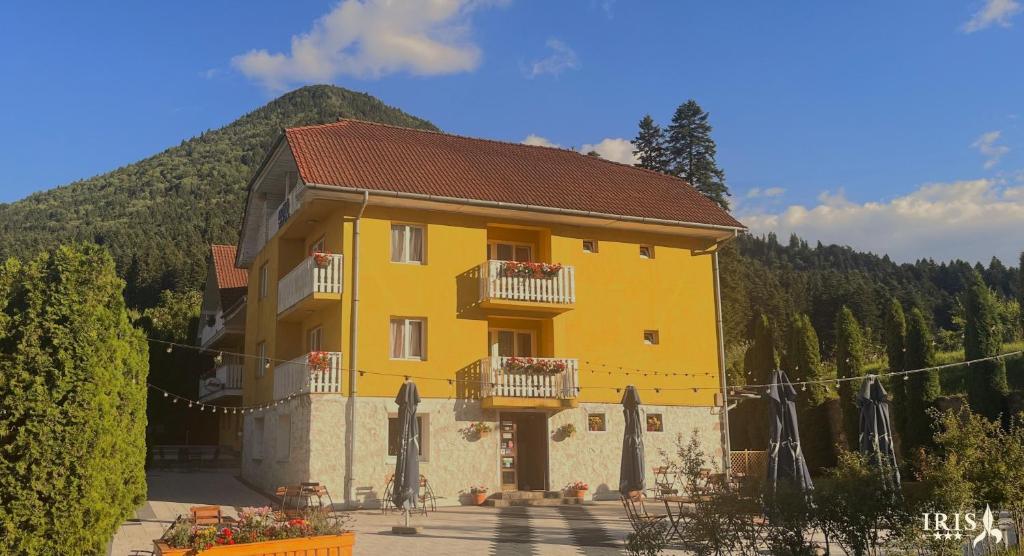 a yellow building with balconies and a mountain at Pensiunea Iris in Băile Tuşnad