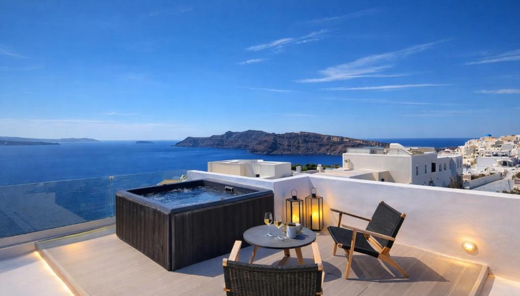 a balcony with a hot tub and a table and chairs at ArmonOia Suites Santorini in Oia