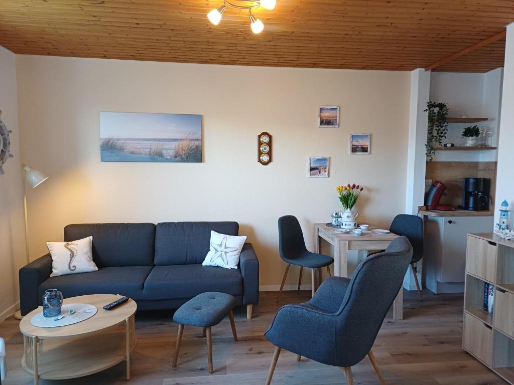 a living room with a blue couch and chairs at Sielpferdchen Bensersiel in Bensersiel