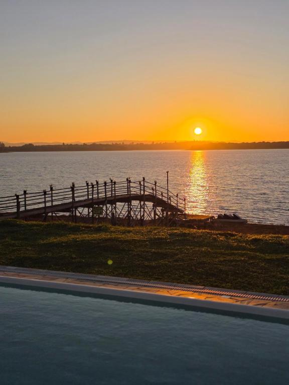a sunset over a body of water with a pier at Riviera Barão de Antonina - Chalés na Represa - Piscina vista incrível in Barão de Antonina