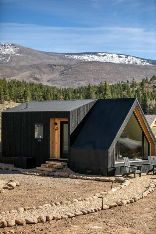 a house with a black roof in the mountains at A-Frame Cliffside Studio Cabins in South Fork