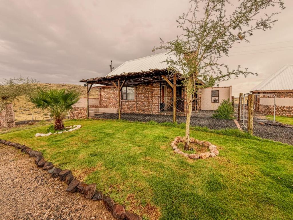 a house with a tree in a yard at Carlo's Mountain Lodge in Usakos