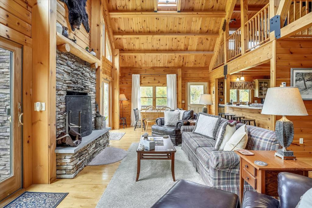 a living room with a stone fireplace in a log cabin at Perry Hill Escape in Waterbury