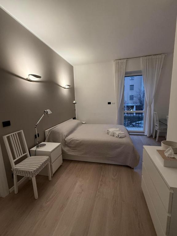 a bedroom with a bed and a chair and a window at Appartamento Laghetto in Segrate