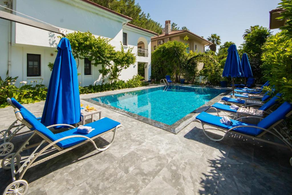 a swimming pool with blue chairs and umbrellas at Villa Cecilia in Göcek
