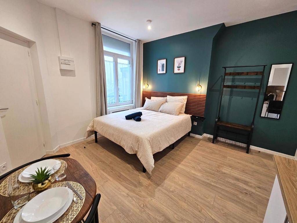 a bedroom with a bed and a table in it at LD Atmosphère in Saint-Quentin