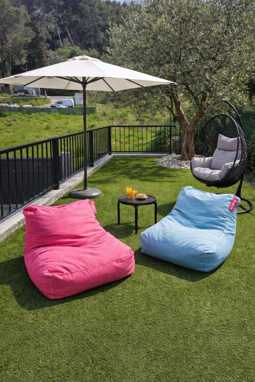 two bean bags sitting on the grass under an umbrella at Mougins Centre - Bastide pierre rénovée spa et piscine privé in Mougins