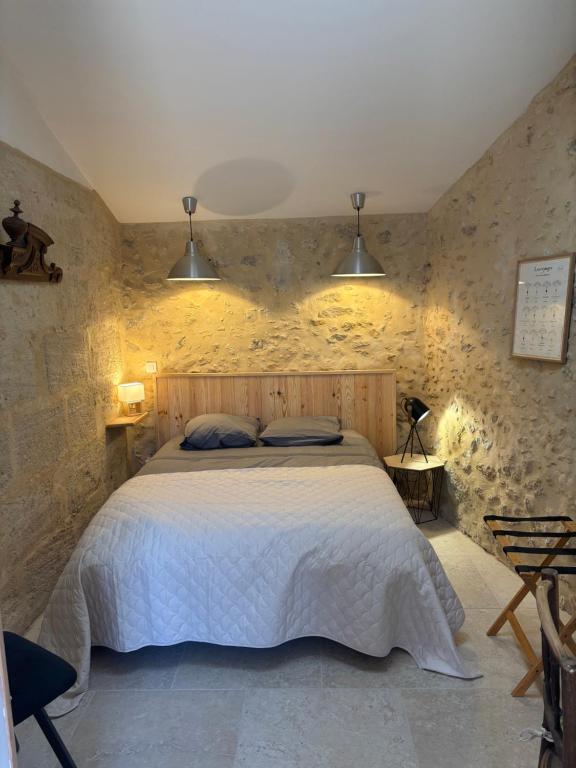 a bedroom with a large bed in a stone wall at l'atelier by Emma in Bommes