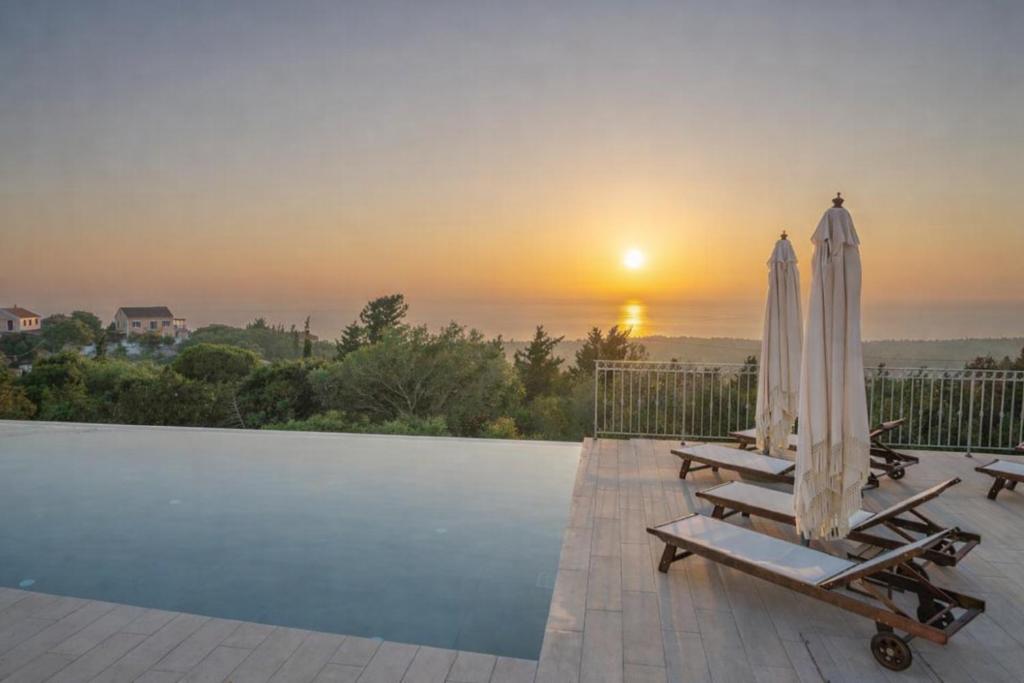 a pool with two umbrellas and two lounge chairs at Hellosummer Boutique suites,near fiscardo! in Andipáta Erísou