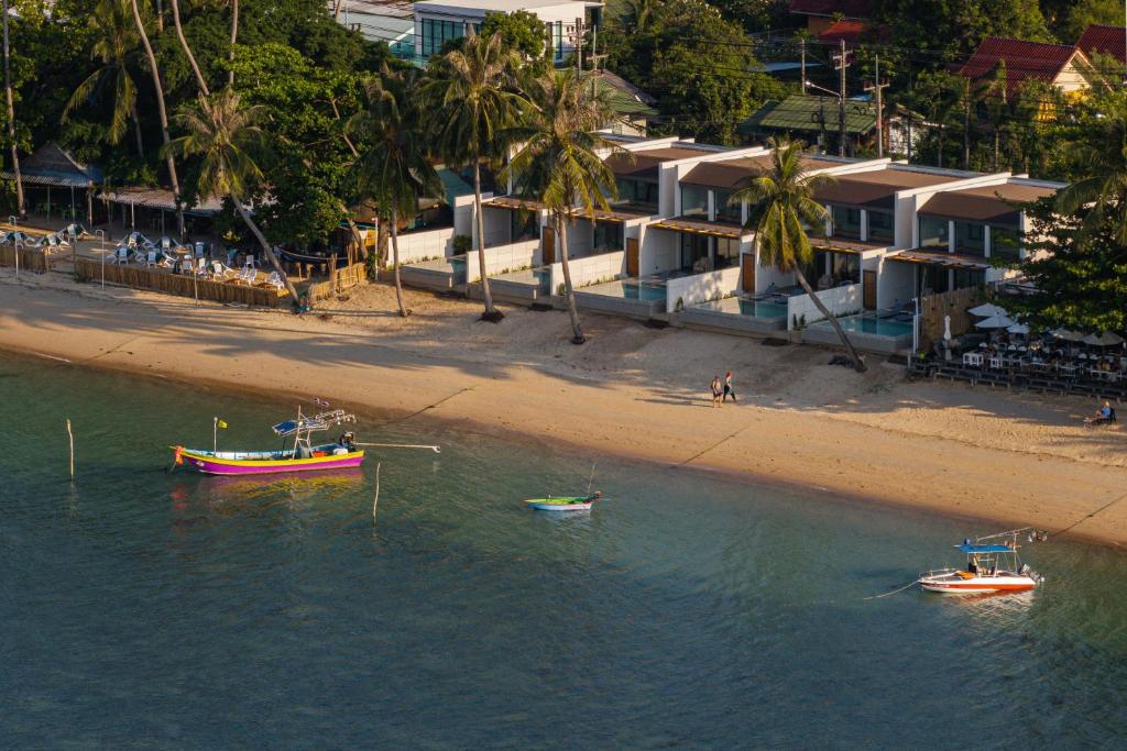 two boats in the water next to a beach at Pano Samui Beachfront Villas in Nathon Bay
