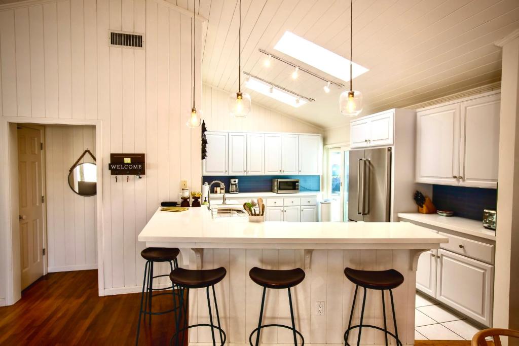 a kitchen with a white counter and three stools at Beachbound Bliss in Del Mar in San Diego