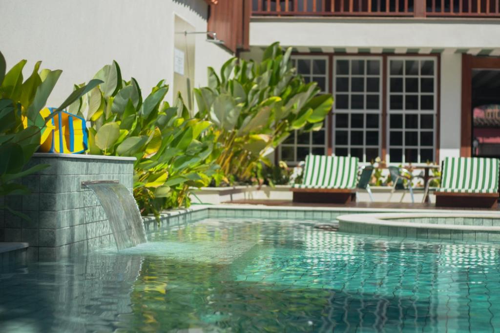 a swimming pool with two lawn chairs and a swimming pool at Pousada Valhacouto in Paraty