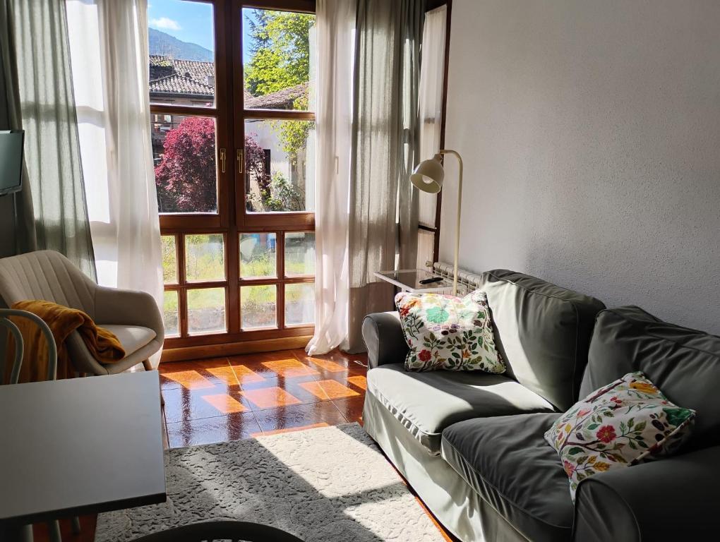 a living room with a couch and a large window at Céntrico apartamento en el casco antiguo de Potes in Potes