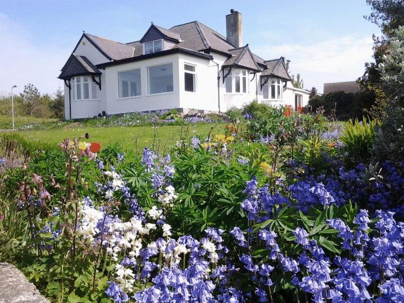 a house with a garden of flowers in front of it at Castellor Bed & Breakfast in Cemaes Bay