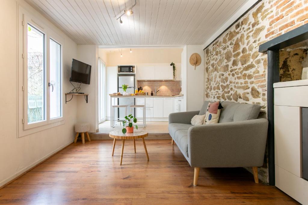 a living room with a couch and a brick wall at Maison Centre ville in La Roche-sur-Yon