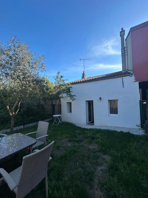 a white house with a table and chairs in the yard at La Petite Maison in Toutlemonde