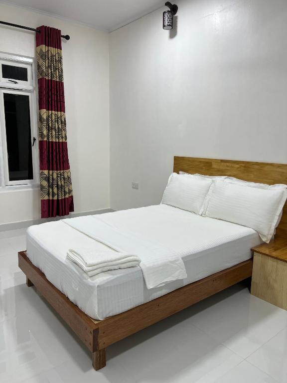 a bedroom with a bed with white sheets and a window at Athireege in Manadhoo