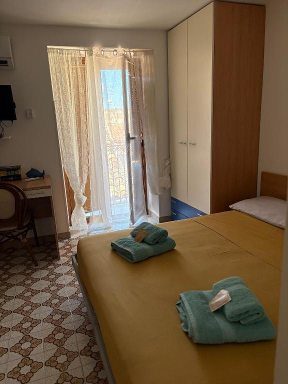 a bedroom with two green towels on a bed at Costa House in Cefalù