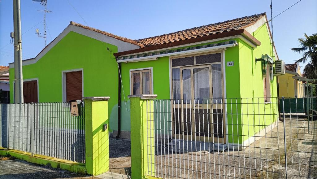 a green and yellow house with a fence at Casa Nonno Maiti in Scardovari