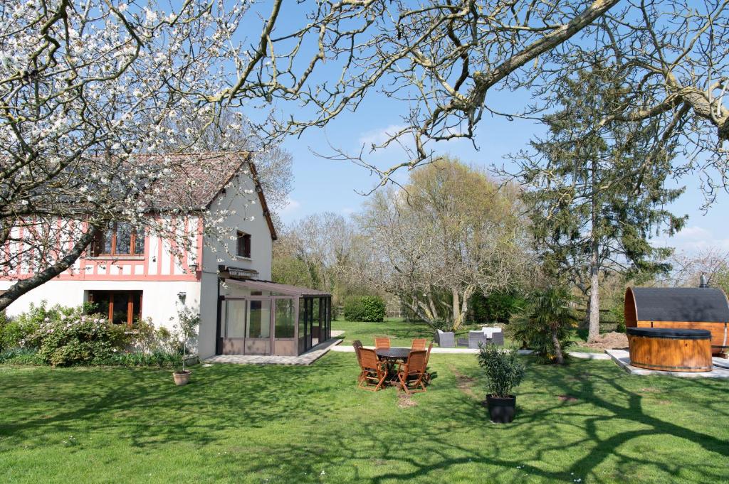 a garden with a house and a table and chairs at La Ronce maison d hote - piscine SPA in Rouvres