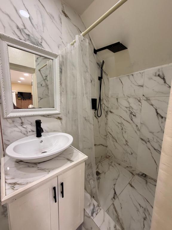 a white bathroom with a sink and a mirror at Very Ralaxing in Saint Georgeʼs