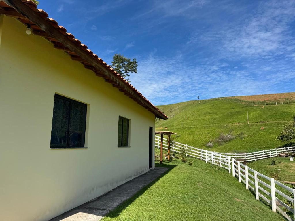 a white house with a fence next to a field at Recanto Catarina in Cunha