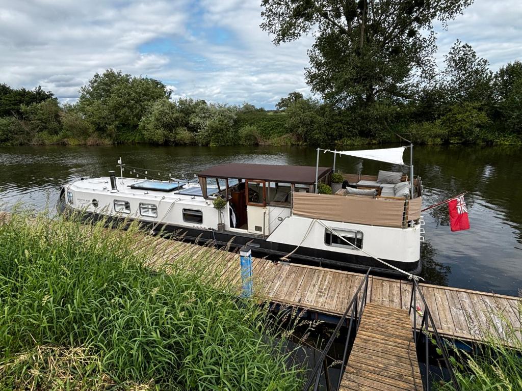a boat is docked at a dock on a river at Unique 2 Bed Waterside Retreat Pet Friendly in Upton upon Severn