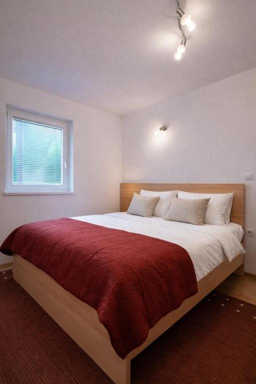 a bedroom with a large bed with a red blanket at Apartment Seka in Podčetrtek