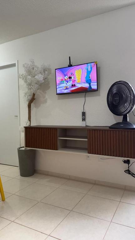 a flat screen tv on a wall with a fan at Lazer na linha verde in Camaçari