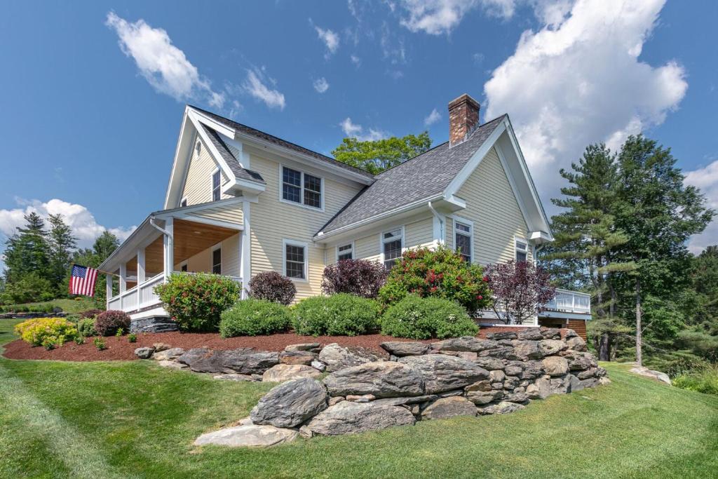 a white house with a stone retaining wall at Village Lodge in Stowe