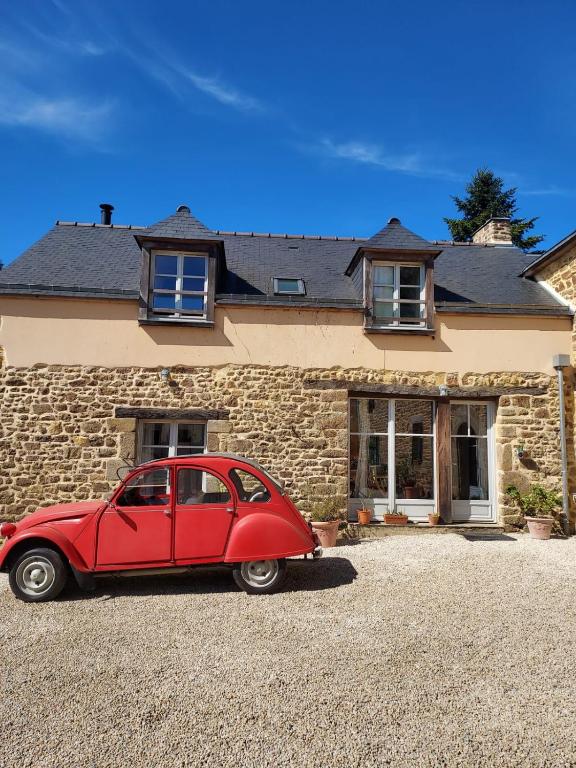 a red car parked in front of a stone house at Gîte Baumelin près de Dinan in Guenroc