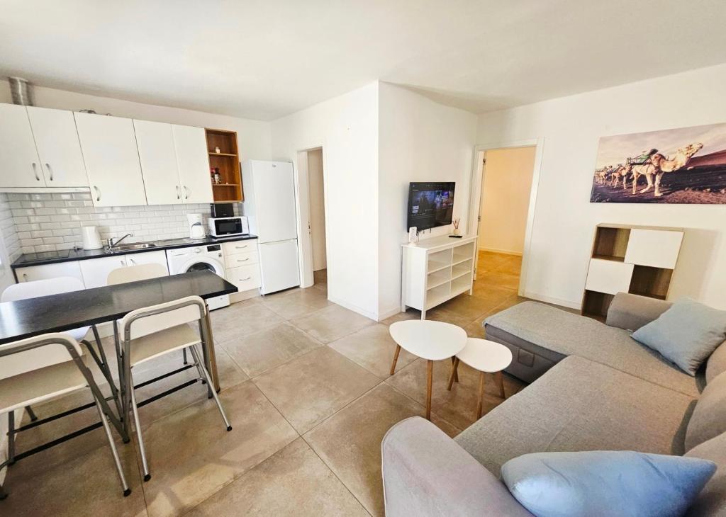 a living room with a couch and a table and a kitchen at Bungalow Alma Playa Roca in Costa Teguise