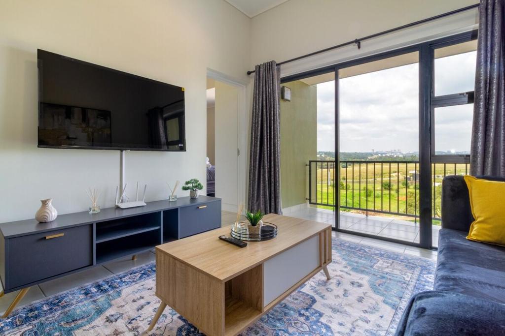 a living room with a couch and a large window at The Greenlee Grove in Sandton