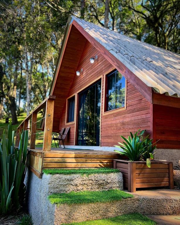 a small wooden cabin with a porch and a bench at Refúgio do Lago in Fraiburgo