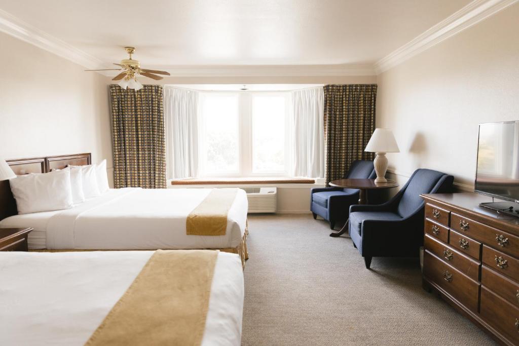 a hotel room with two beds and a chair at Historic Santa Maria Inn in Santa Maria