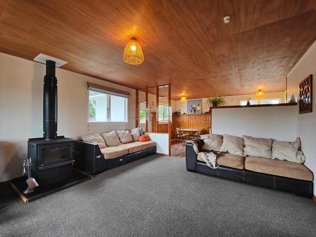 a living room with a couch and a stove at Arrive and Revive Te Anau in Te Anau