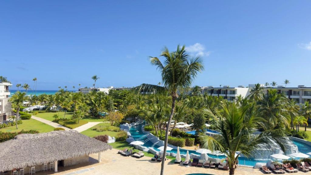 Aerial view of resort grounds with pool, beach access, palm trees, and accommodations.