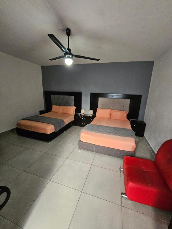 a bedroom with two beds and a red couch at Hostal Livette in Guadalajara