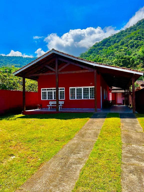 a red building with a grass yard in front of it at Casa do Sapê 5 dormitórios em Ubatuba in Ubatuba
