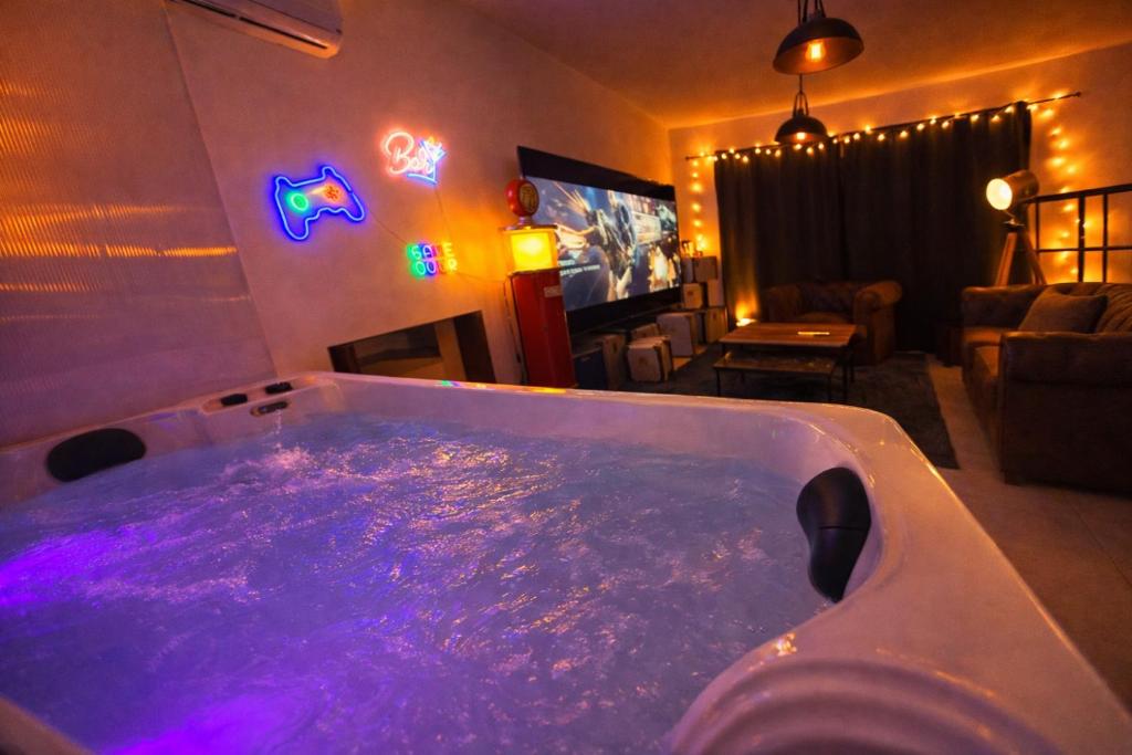 a large tub in a living room with purple lighting at Jacuzzi et cinéma privatif P1 in Pessac