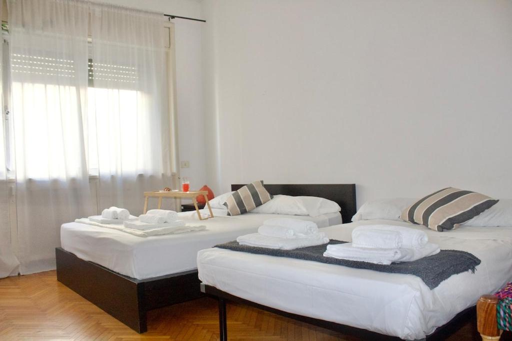 two beds sitting next to each other in a room at Iconic 3-BR Home Steps from Duomo in Milan