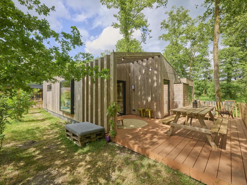 a small wooden cabin with a picnic table on a deck at Cabin 22 in Zutendaal