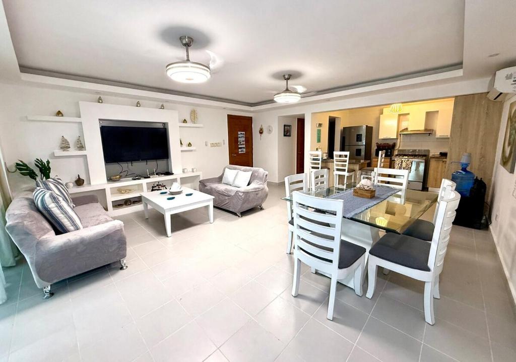 a living room with a table and chairs and a television at Palm Paradise Condo Pool & Beach in Punta Cana