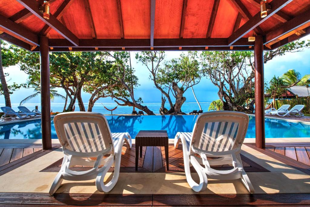 eine Terrasse mit 2 Stühlen, einem Tisch und einem Pool in der Unterkunft Maui Palms in Korolevu