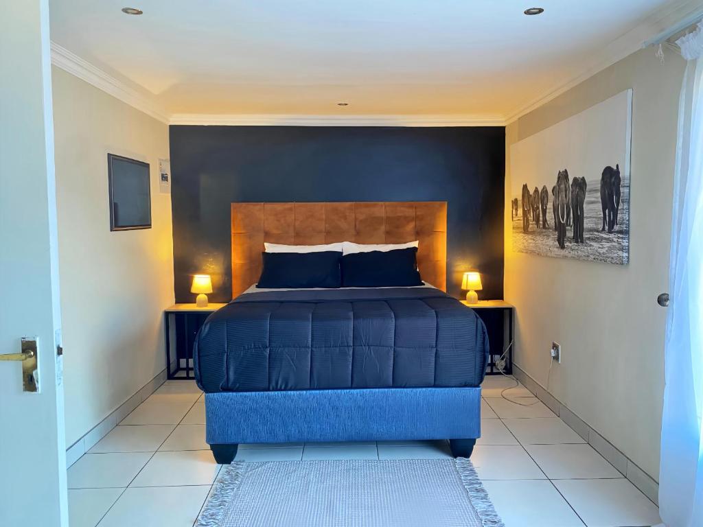 a bedroom with a blue bed and two lamps at Modern Luxe Escape in Kempton Park