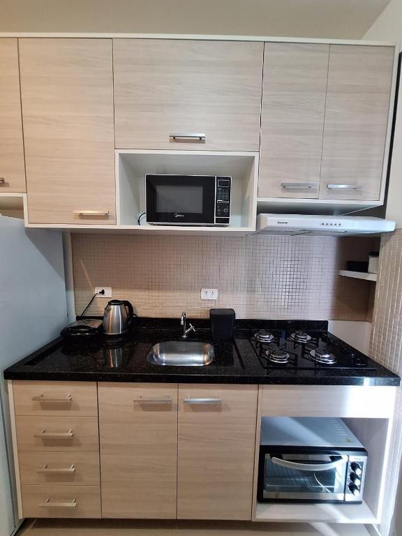 a small kitchen with a sink and a microwave at Estúdio Fit Caiobá - Matinhos in Matinhos